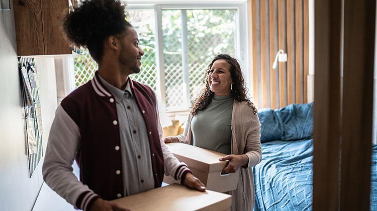 Mother helping son carry moving boxes to move out from parent’s home.